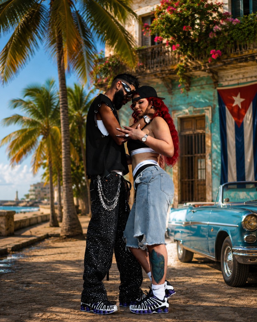 Anita Dieppa y El Yonki en La Habana: calle adoquinada, arquitectura colonial, auto clásico y bandera cubana al fondo